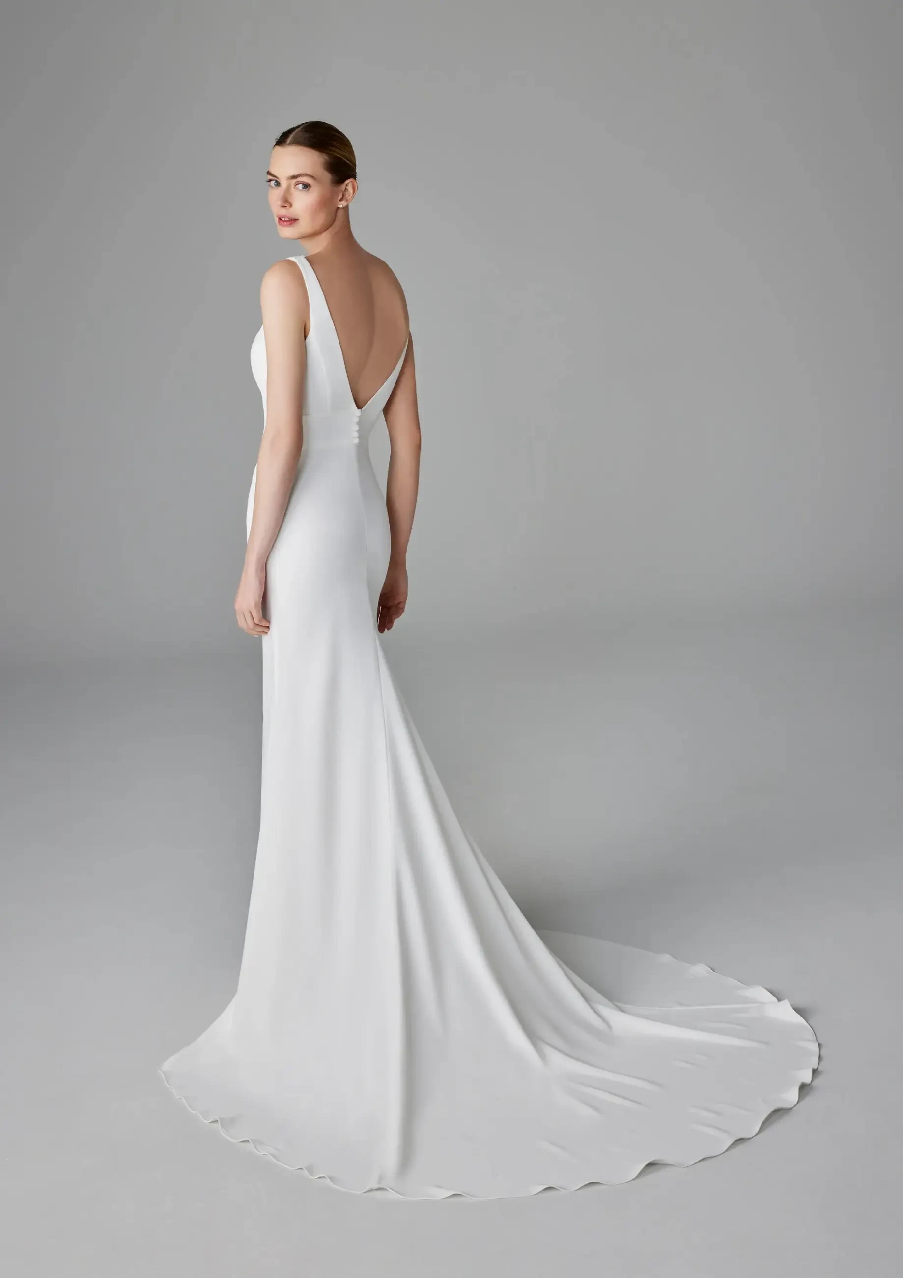 Model is wearing a sleek crepe mermaid wedding dress with a v neckline